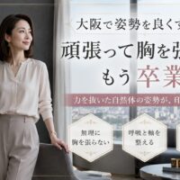 大阪の街並みを望む洗練された室内で、手帳を持つ上品な女性が自然体で立ち、胸を張らずに呼吸と体の軸を整えて姿勢を良くする方法を示している。