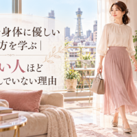 大阪の通天閣を望む明るく上品な部屋で、バッグを持つ女性が自然体で軽やかに歩き、大阪で身体に優しい歩き方と力まない姿勢を表している。