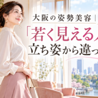 大阪城を望む明るく上品な部屋で、白いブラウスと淡いピンクのスカート姿の女性が美しく立ち、大阪の姿勢美容で若々しい印象を整える様子を示している。